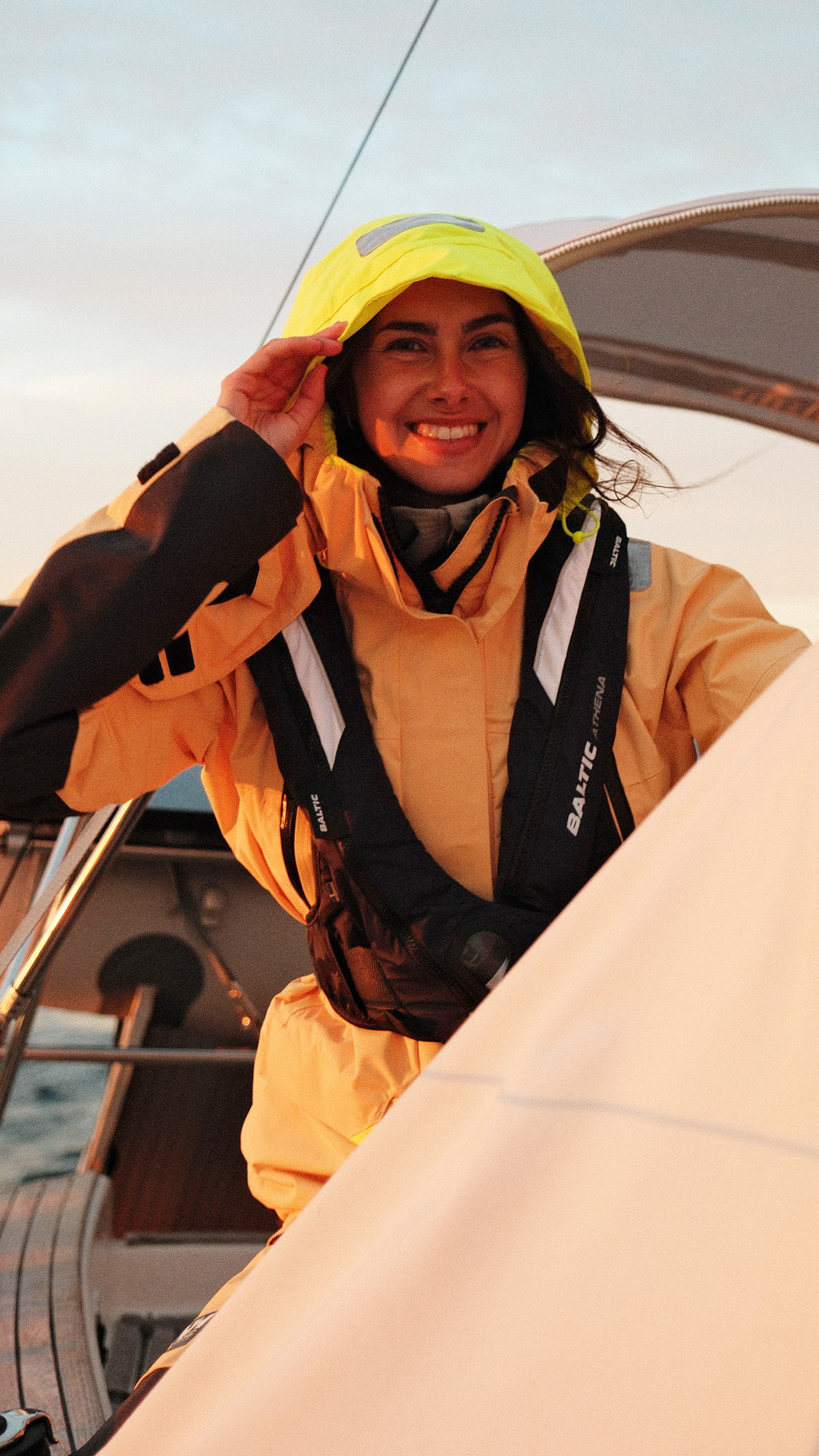 En tjej ler och blickar ut på havet från en segelbåt.